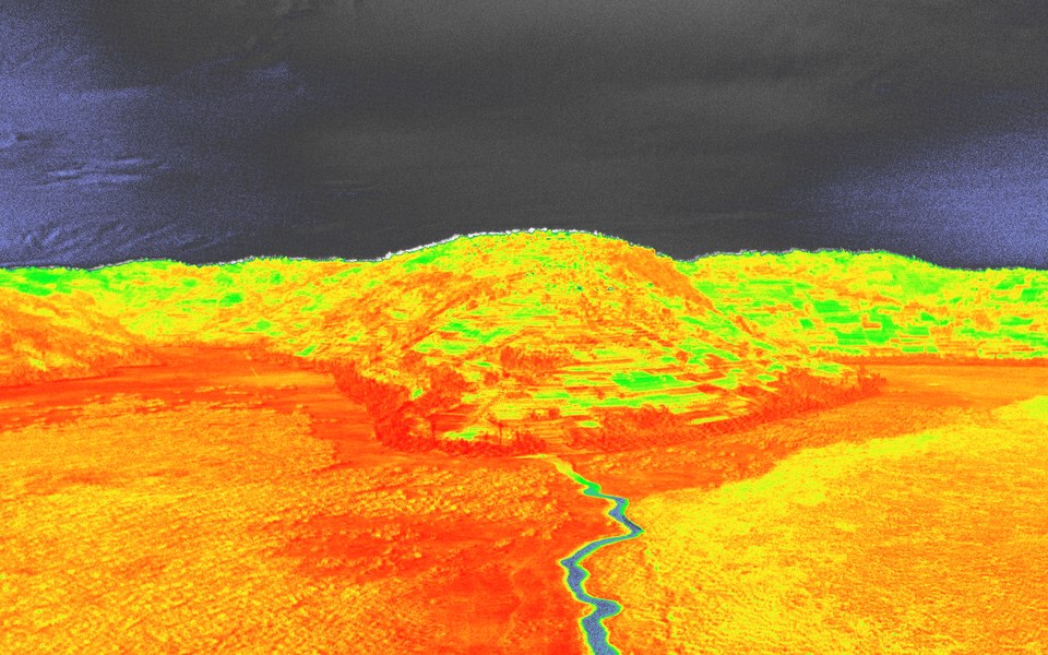 False colour aerial render of a valley showing vegetation and a watercourse picked out against bare ground